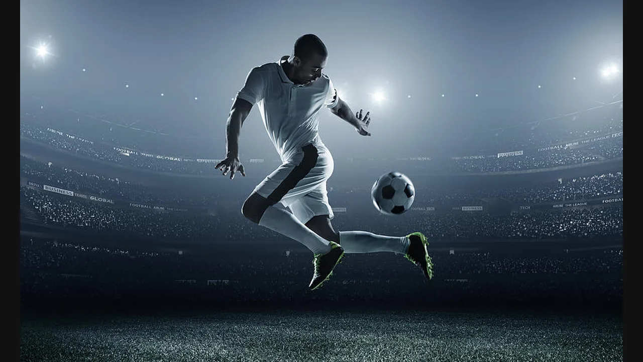 Photograph of a soccer player striking the ball in mid-air in a floodlit stadium
